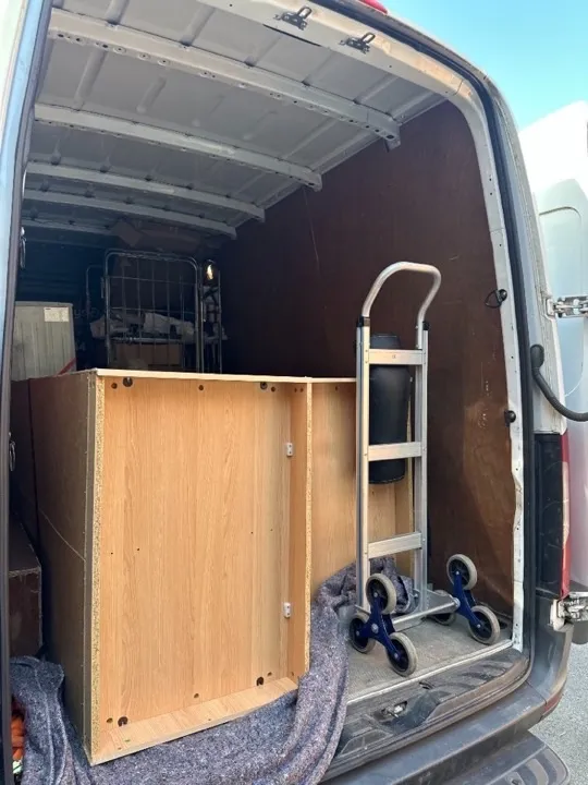 Business moves — office desk in van Office desk and cabinet loaded on moving blankets inside a removals van with a stair-climbing hand truck for a business relocation