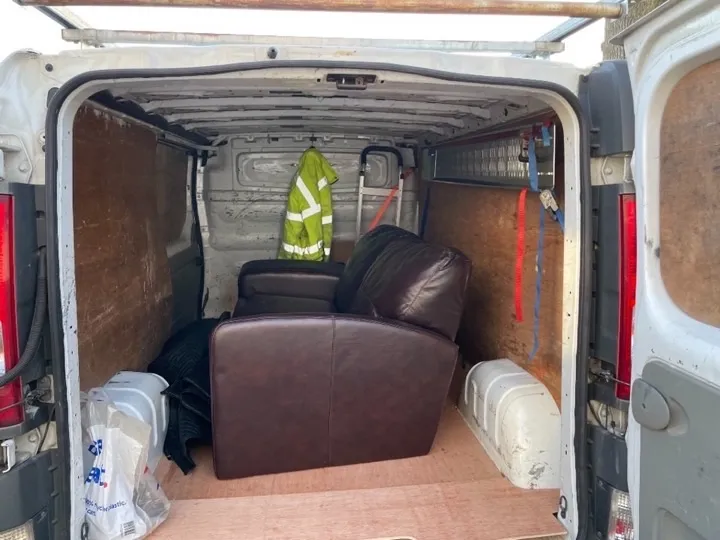 Furniture collection — leather sofa transport Dark brown leather sofa secured inside a furniture collection van with moving blankets and tie-down straps