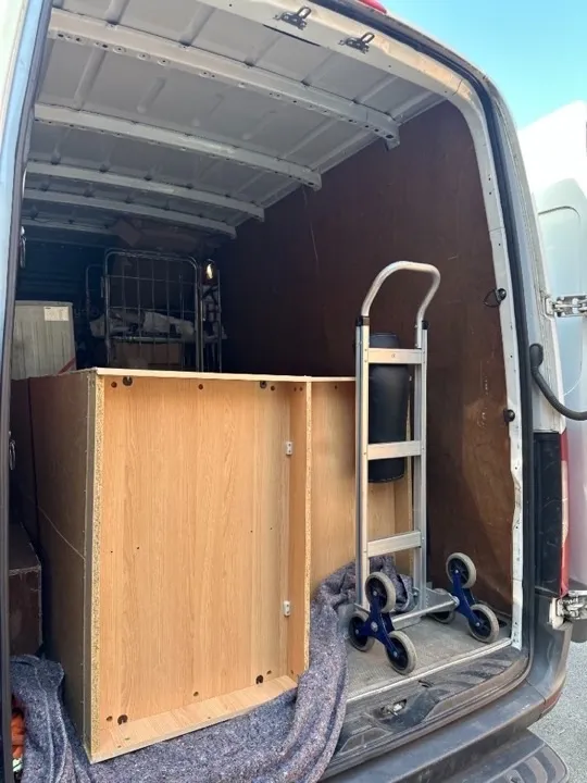 Furniture collection — wardrobe and stair climber Wooden wardrobe cabinet and stair-climbing hand truck inside a furniture collection van for safe transport