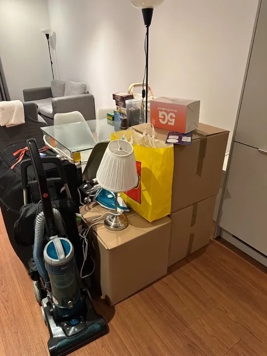 Packing services — household items packed for move Sealed moving boxes with lamp, iron, vacuum cleaner, and luggage packed and ready for a professional home removals packing service