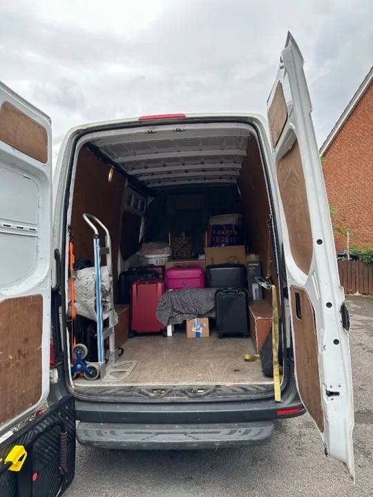 Small moves — van loaded with suitcases and boxes Small move van interior packed with suitcases, cardboard boxes, and a hand truck for a UK studio or apartment relocation