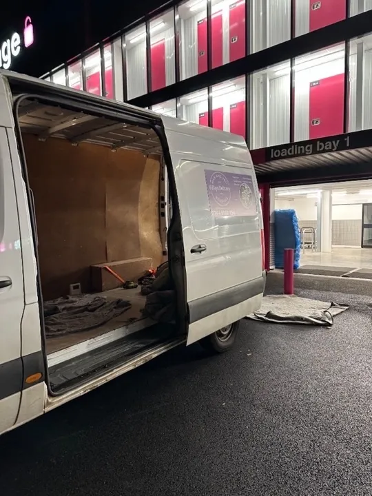 Storage solutions — van at loading bay Removals van with open side door at a self-storage loading bay at night, showing moving blankets and secured items inside